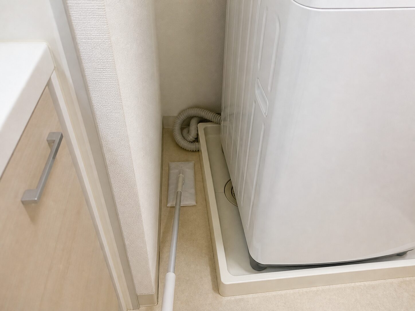 洗濯機横のすき間へ床ワイパーを入れて掃除できる状態