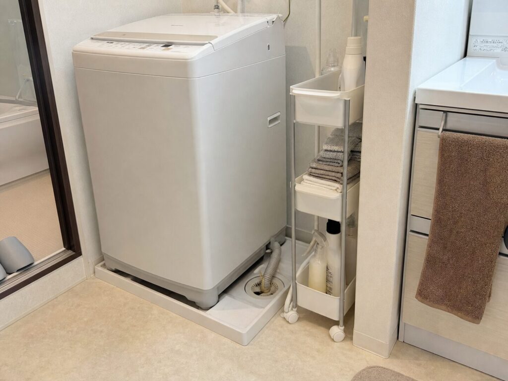 洗濯機横に細いワゴンを置き排水ホースと床の余白を確認している状態