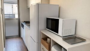 狭いキッチンで専用カウンターへ電子レンジを置き横に皿の置き場と通路を残した配置