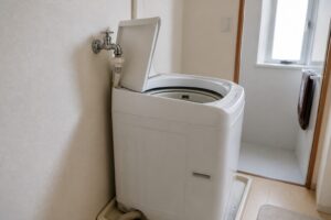 低い蛇口の手前で縦型洗濯機のふたが全開できず止まる様子